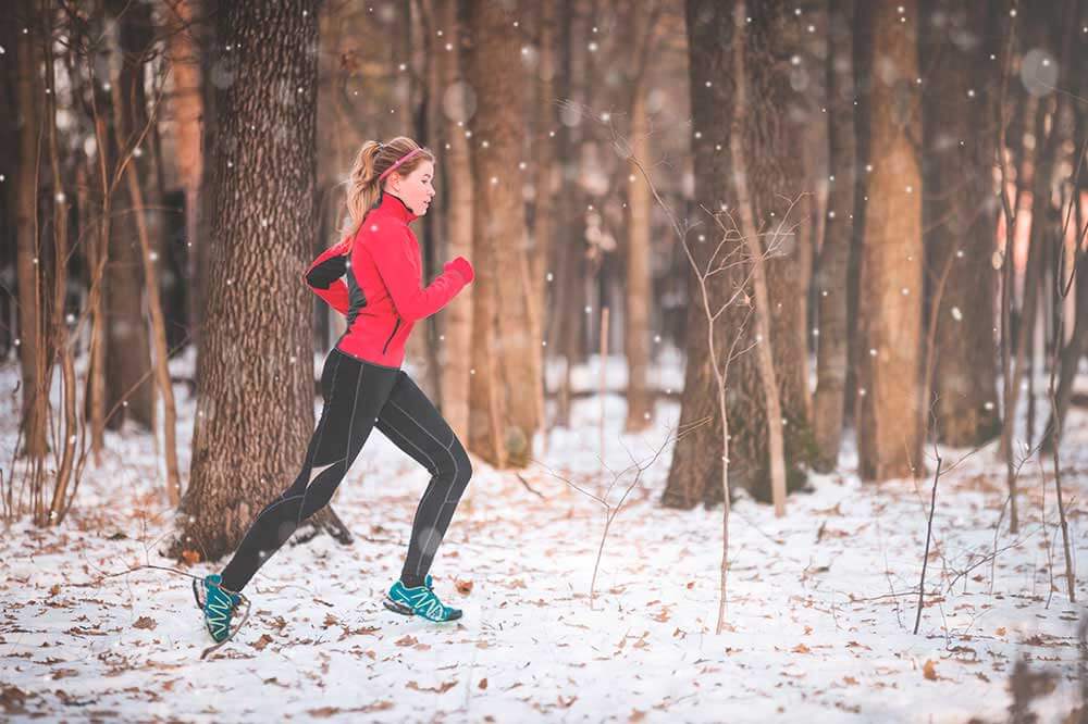 Mujer corriendo en bosque nevado